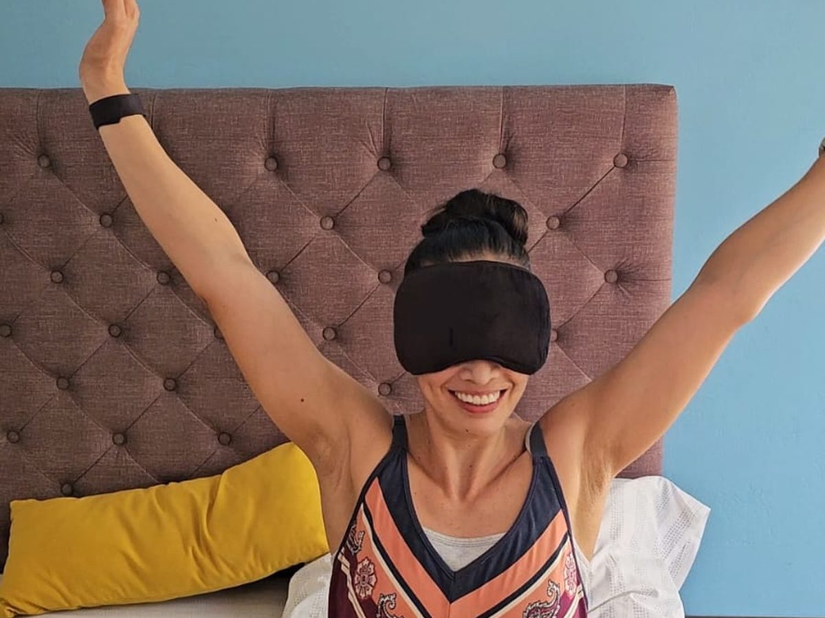 La Dra. Lili Padilla despertando y estirándose en la cama, con antifaz para dormir